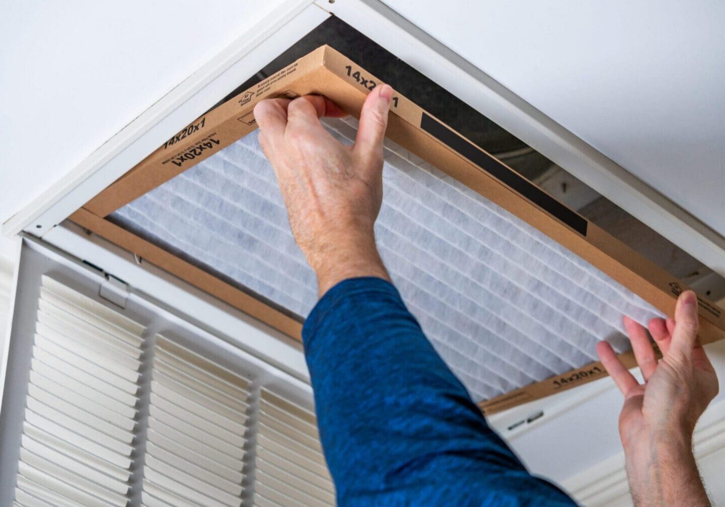 Hands changing pleated ceiling vent air filter